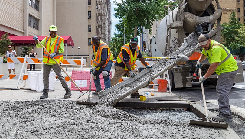 Construction workers laying down cement for a new sidewalk corner
