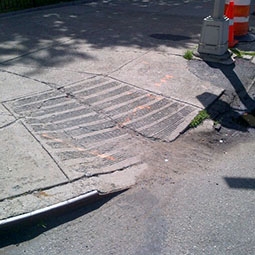 A pedestrian ramp with cracks in the concrete and curb